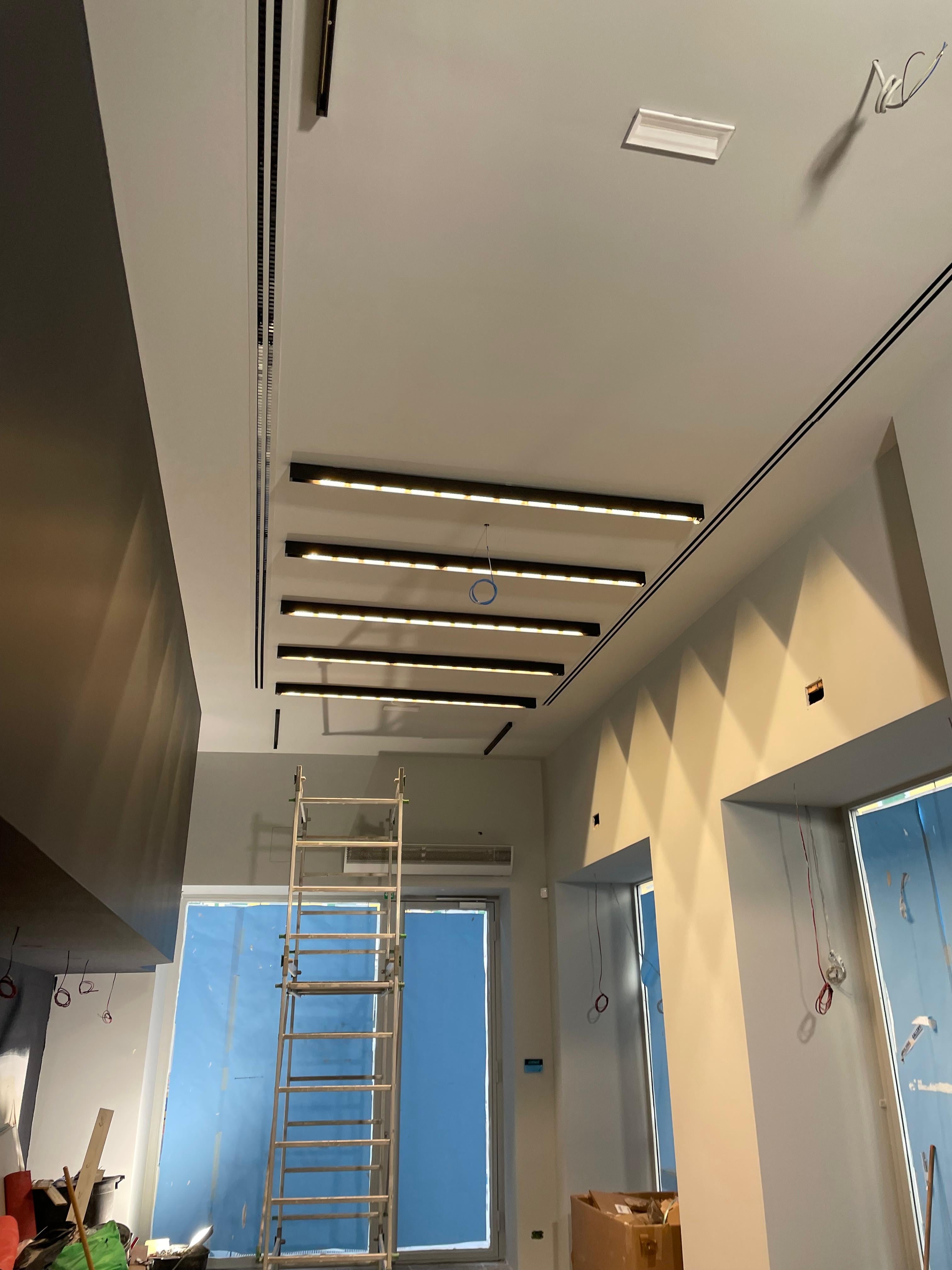 Soffitto del negozio in fase di cantiere con binari LED sospesi appena installati